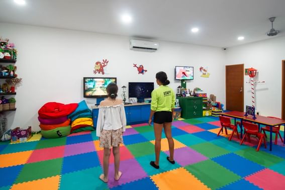 2 kids watching TV while standing in an indoor area play area at Plaza Pelicanos Club Beach Resort
