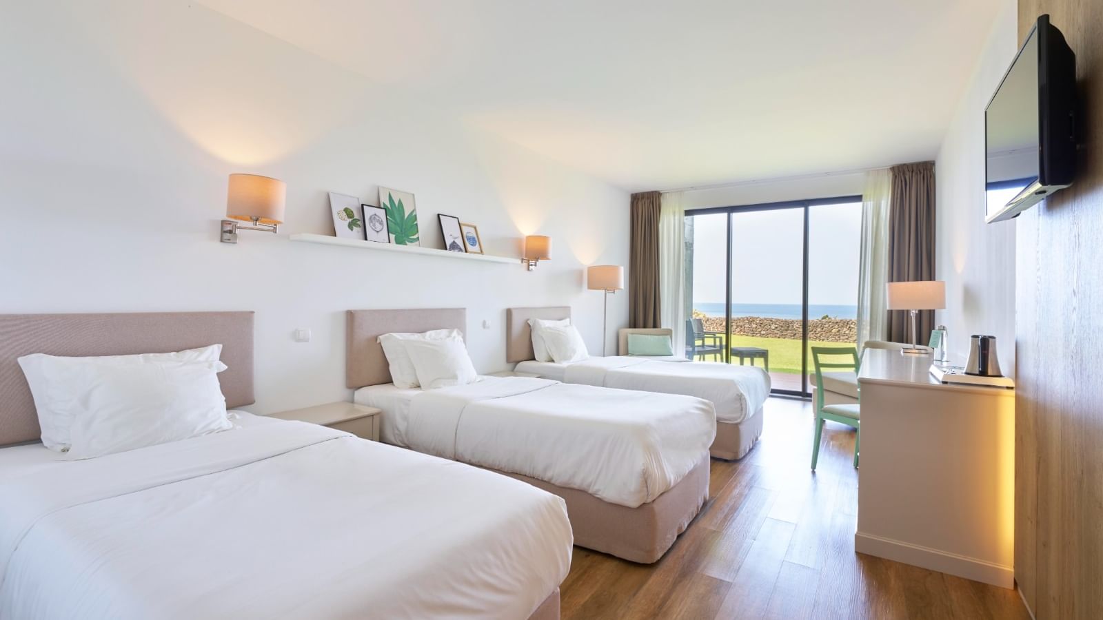 TV and workspace facing the cozy beds in Family Room with wooden flooring at Caloura Hotel Resort