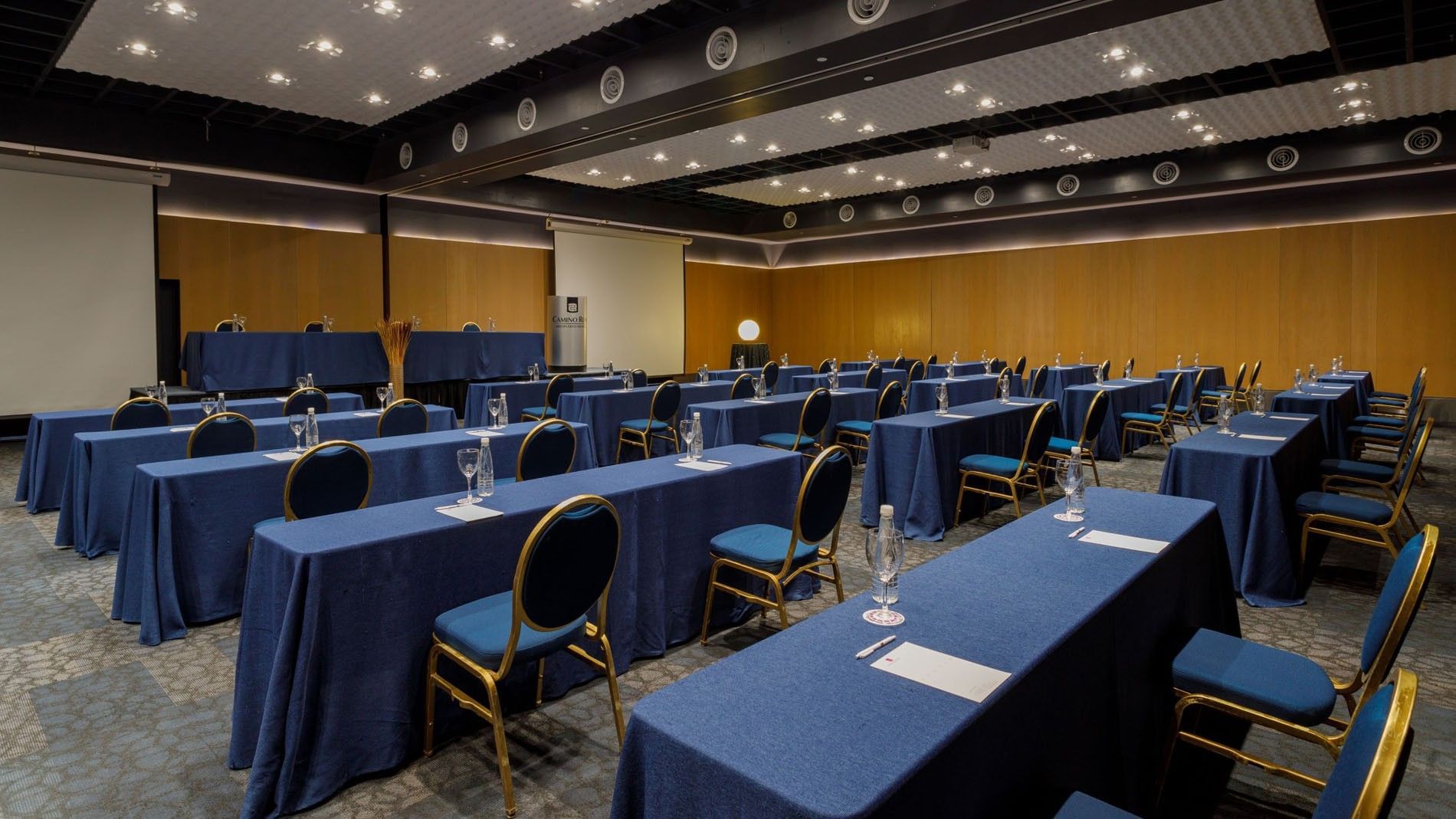 Conference room with rows of blue tables and chairs set up for a meeting at Camino Real Aeropuerto Mexico