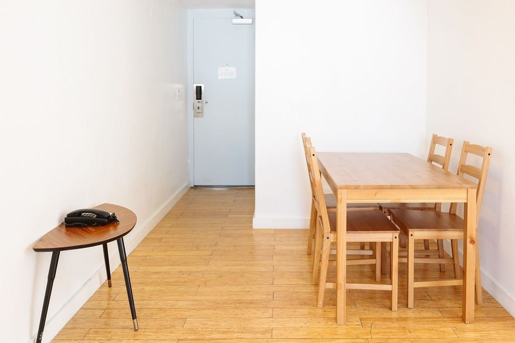 A small dining area with a wooden table and chairs, and a small table with a telephone on it.