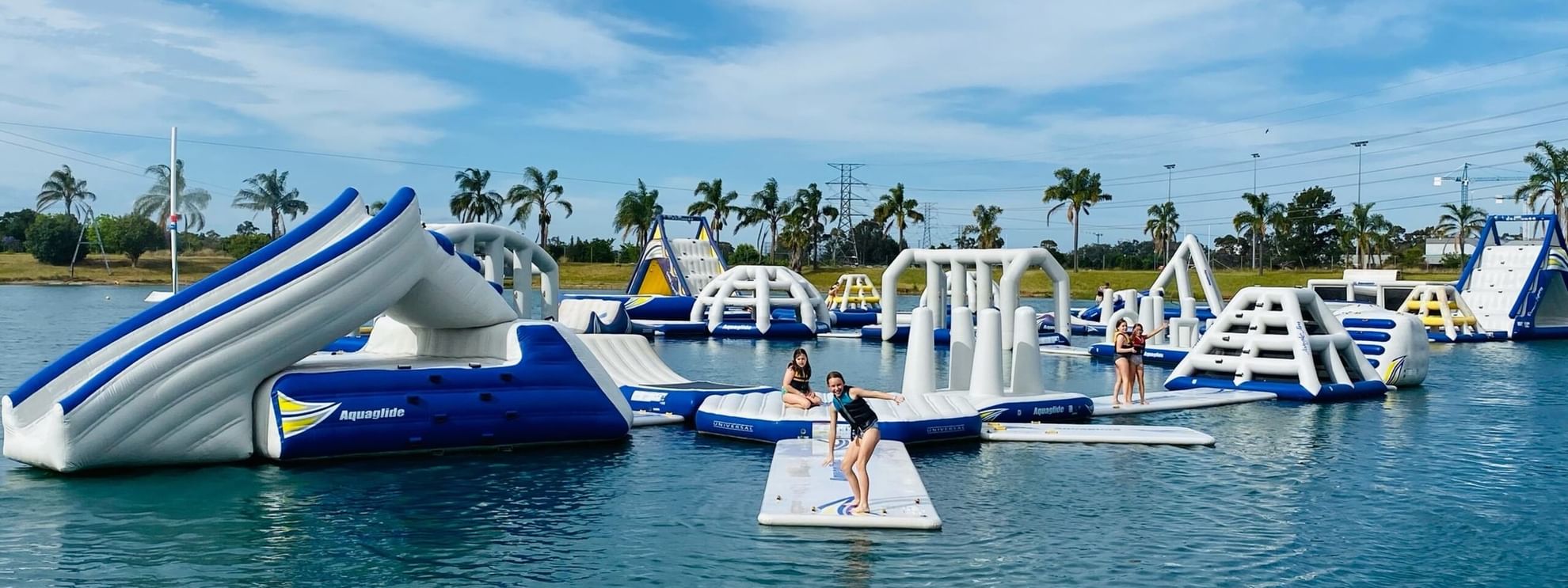 People enjoying Cables Wake & Aqua Park with inflatable obstacles in water.