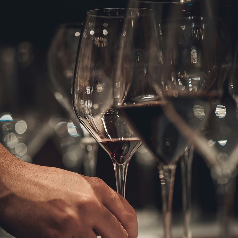 Hand holding a wine glass among many glasses during a wine tasting event.