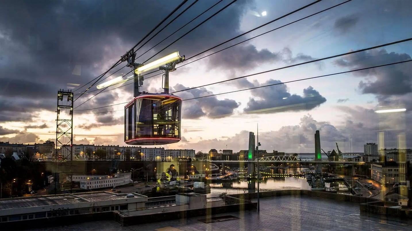 A cable car glides above a cityscape near Oceania Hotels