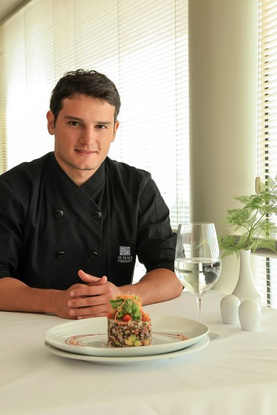 Chef in black uniform presenting gourmet dish with wine glass at Sumaq Machu Picchu Hotel