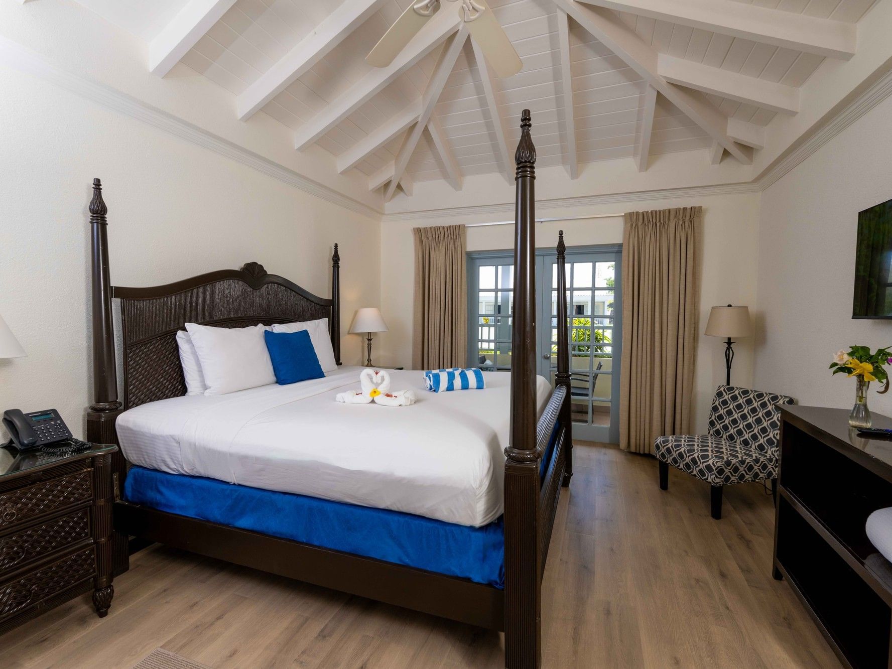 Deluxe Pool View King room with four-poster bed, vaulted ceiling, and balcony access at Savannah Beach Hotel