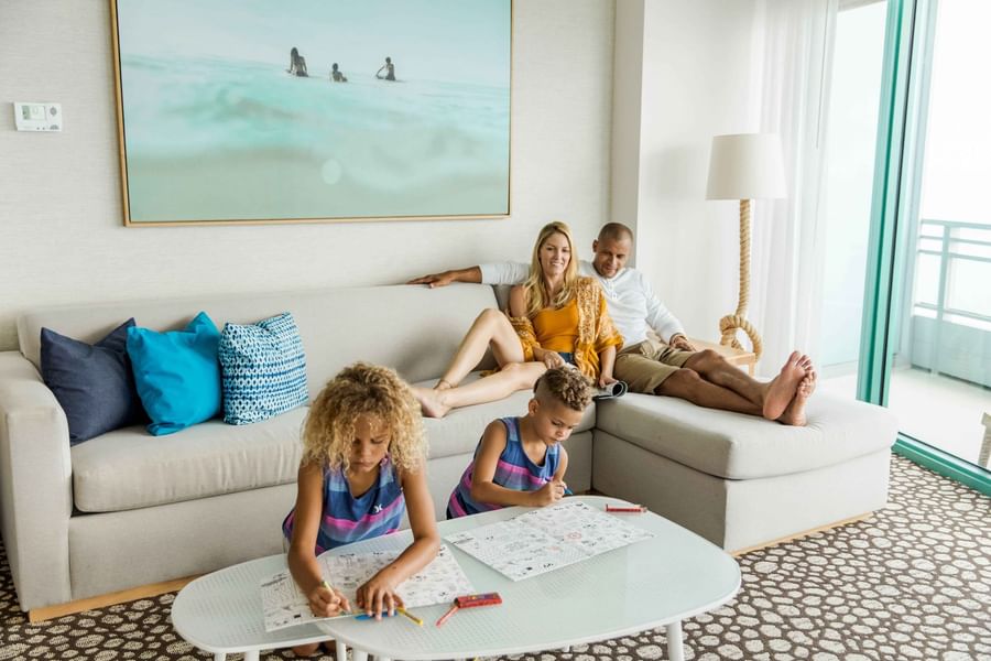 Family relaxing in Two Bedroom Family Suite with cozy furniture and a balcony at The Diplomat Resort