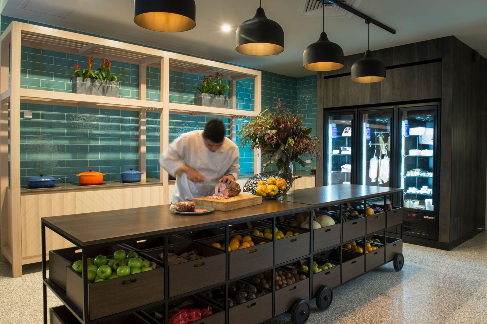 A chef cutting meat in the kitchen of Novotel Barossa Valley