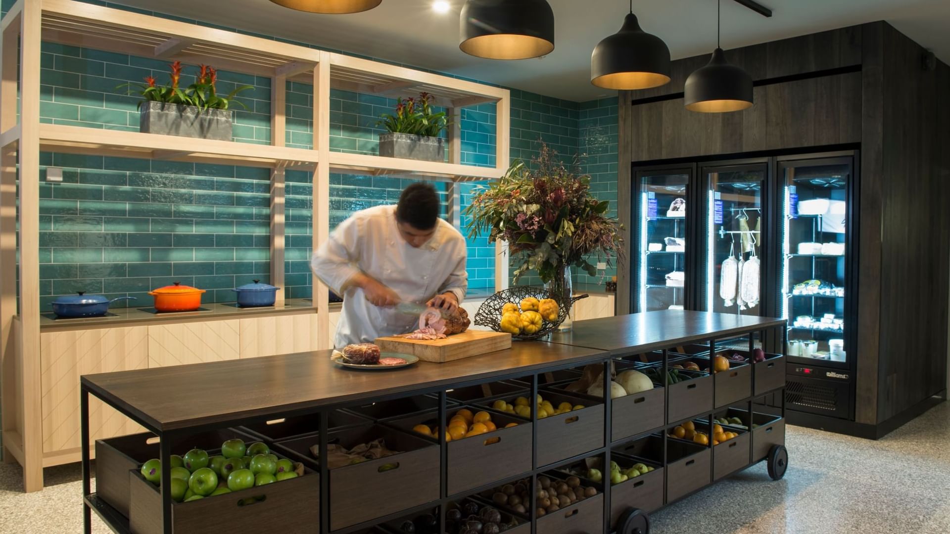 A chef cutting meat in the kitchen of Novotel Barossa Valley