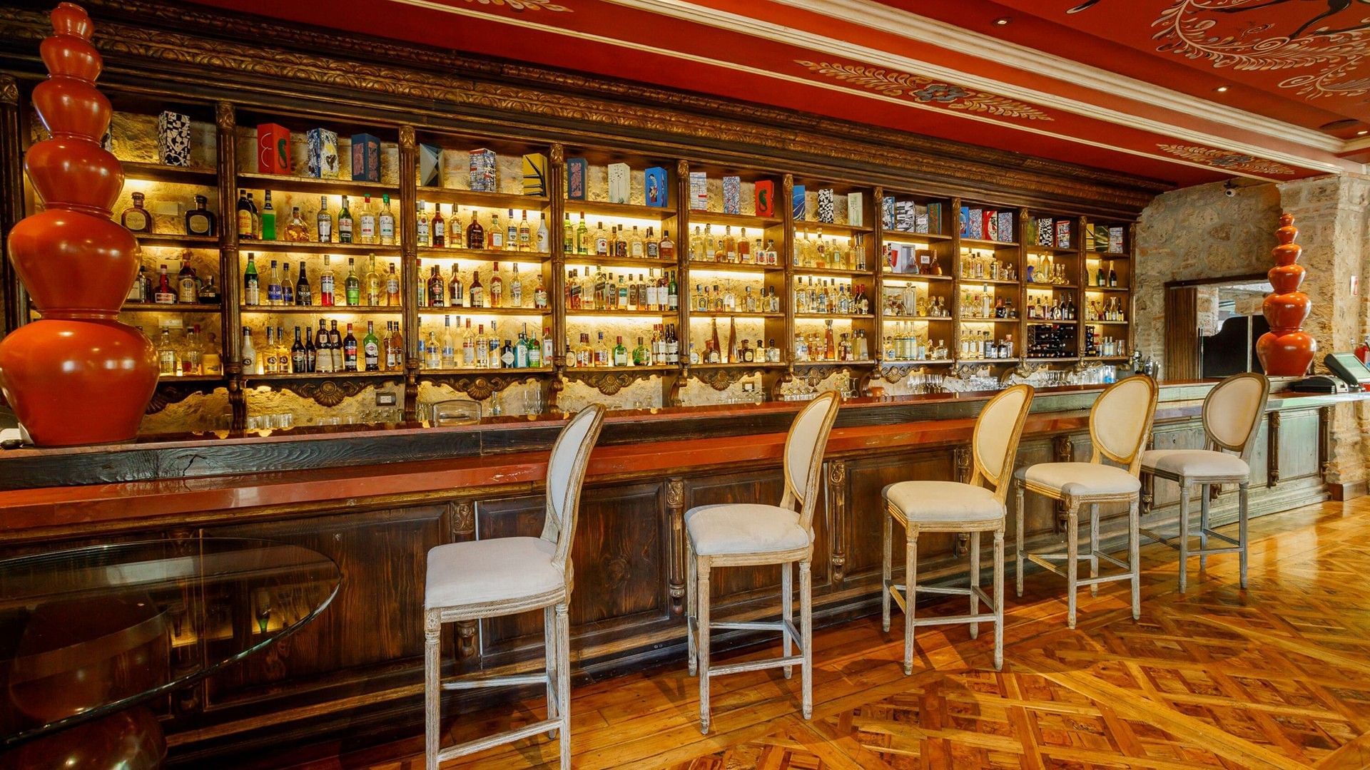 Bar area in Tierra Mia restaurant with white high-back chairs and extensive liquor bottle shelves at Quinta Real Guadalajara