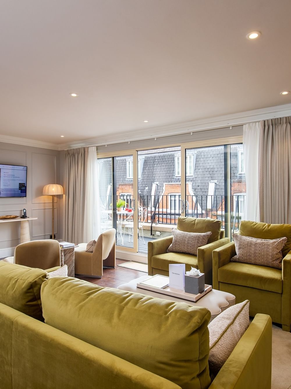 Decorated penthouse living room with green furniture and city view at The Capital Hotel, Apartments & Townhouse