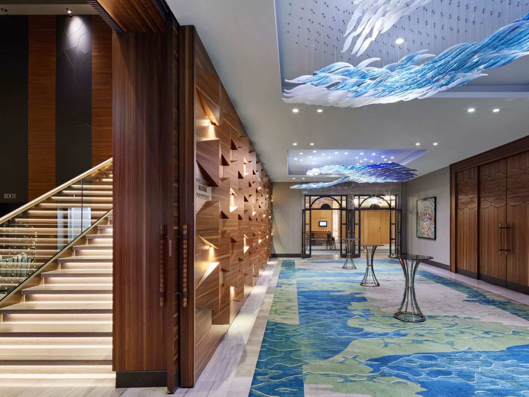 Moderne Lobby mit kunstvollen Deckenleuchten und einem Treppenaufgang im Titanic Chaussee Berlin.