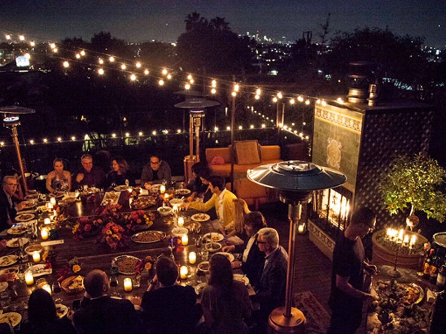 Full Rooftop Buyout with an event space in West Hollywood featuring string lights and a long wooden table at Petit Ermitage