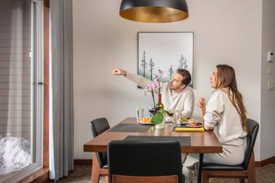 Cozy dining setting with two people enjoying a meal and discussing animatedly at Blackstone Mountain Lodge