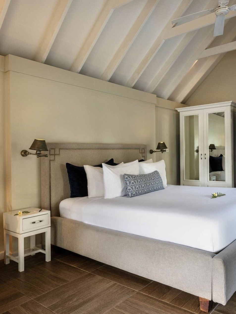 Modern white bed with beside flower vase and open doorway reveals a bathroom in Efate Pool Villa at warwick le lagon-vanuatu