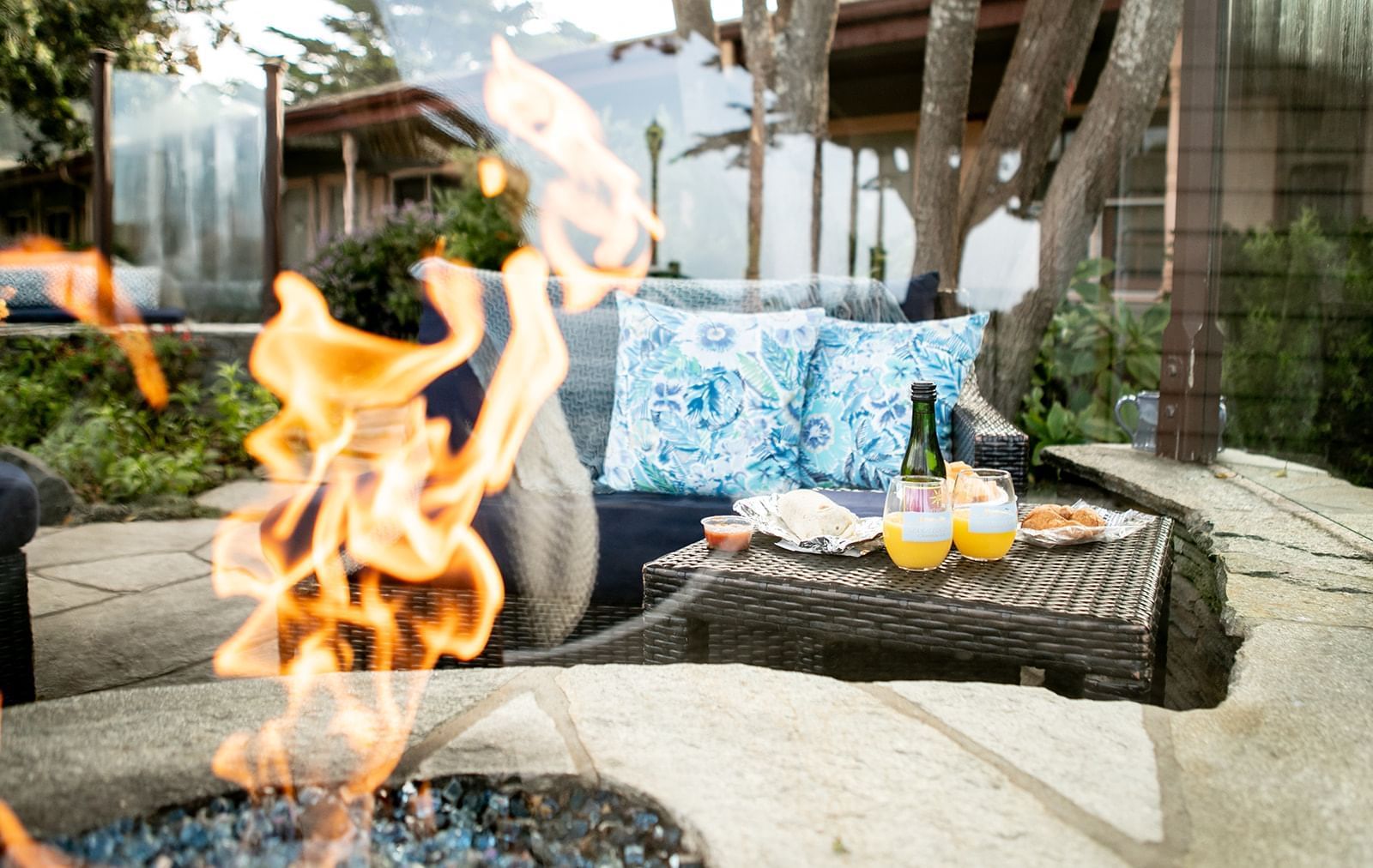 An outdoor seating area with a fire pit, wicker furniture, and a garden.