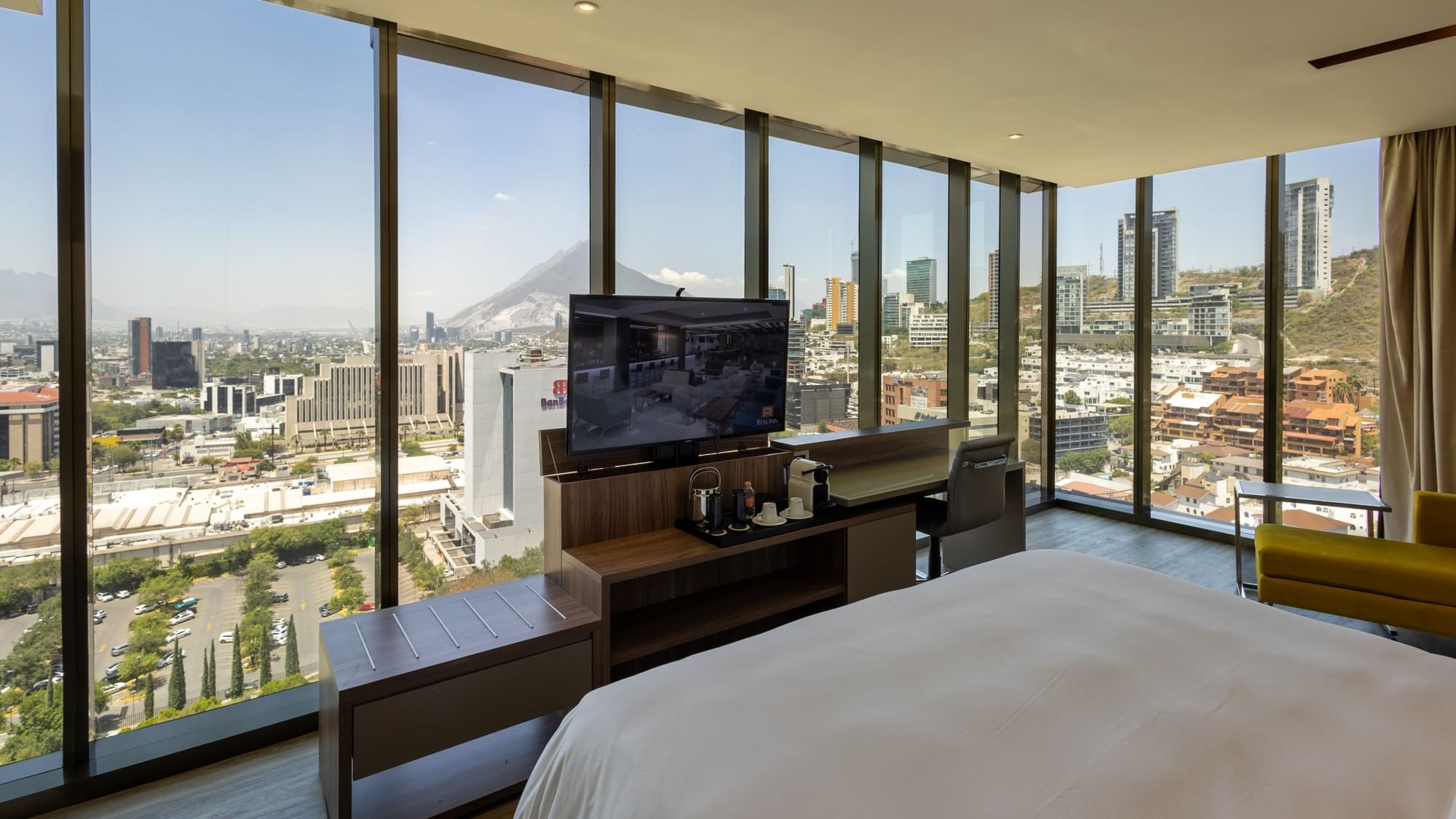 King Junior Suite with floor-to-ceiling windows showcasing panoramic city and mountain views at Camino Real Fashion Drive Monterrey.