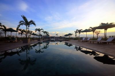 Pool area with sunbeds and palm trees at U Hotels & Resorts