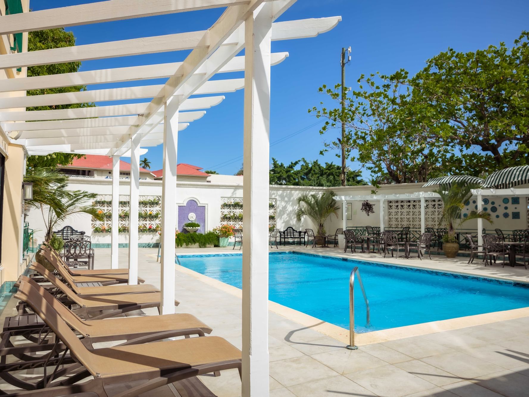 Sunbeds by the outdoor pool at Courtleigh Hotel & Suites