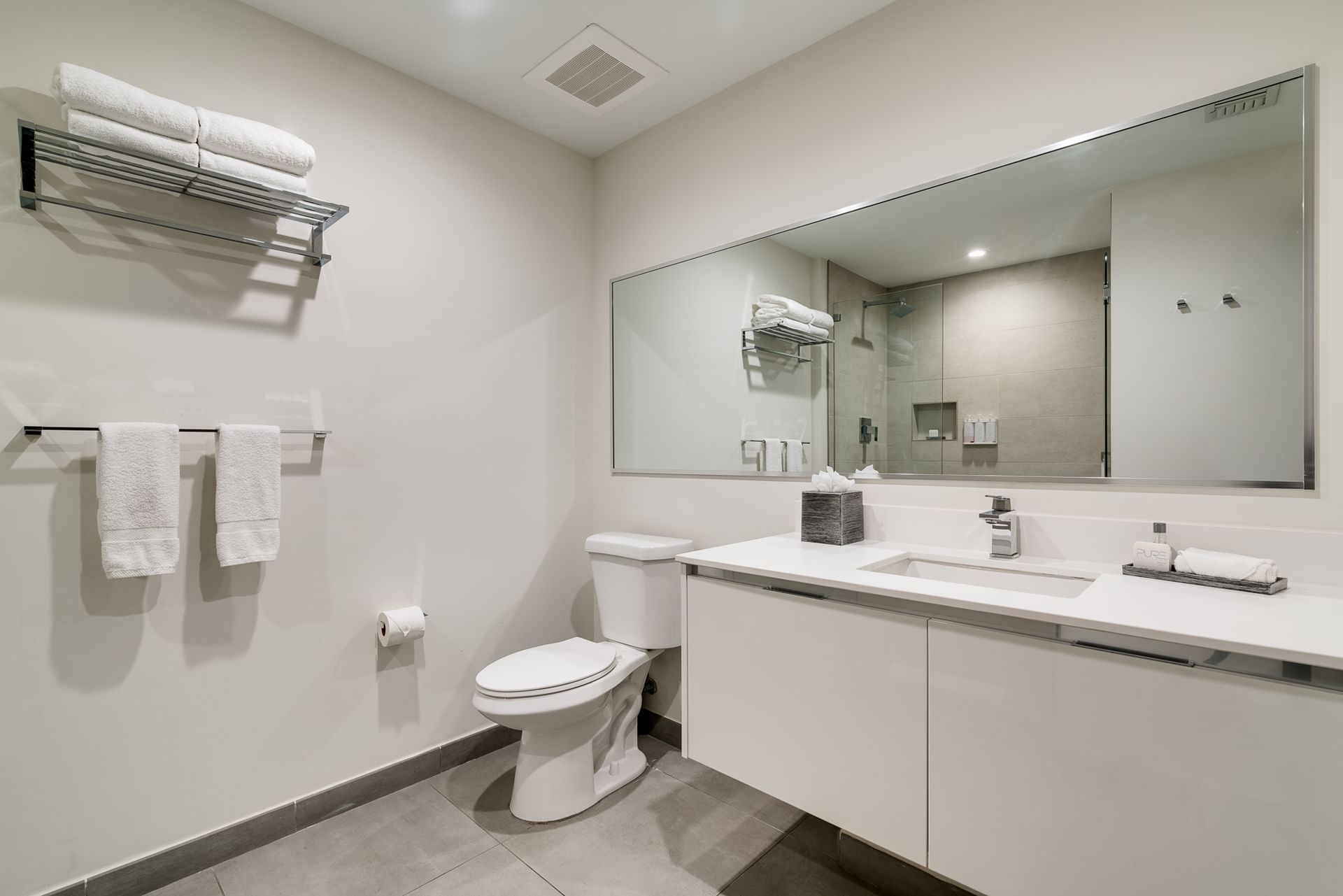 A modern bathroom with a toilet, sink, and mirror.