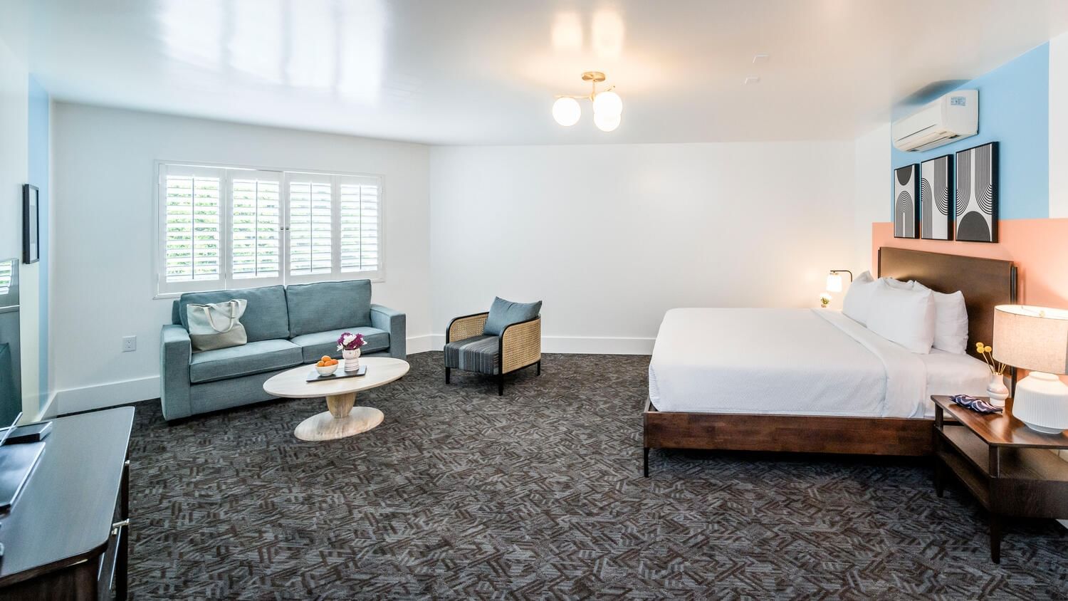A spacious hotel suite with a sofa, coffee table, chair, and king-sized bed.