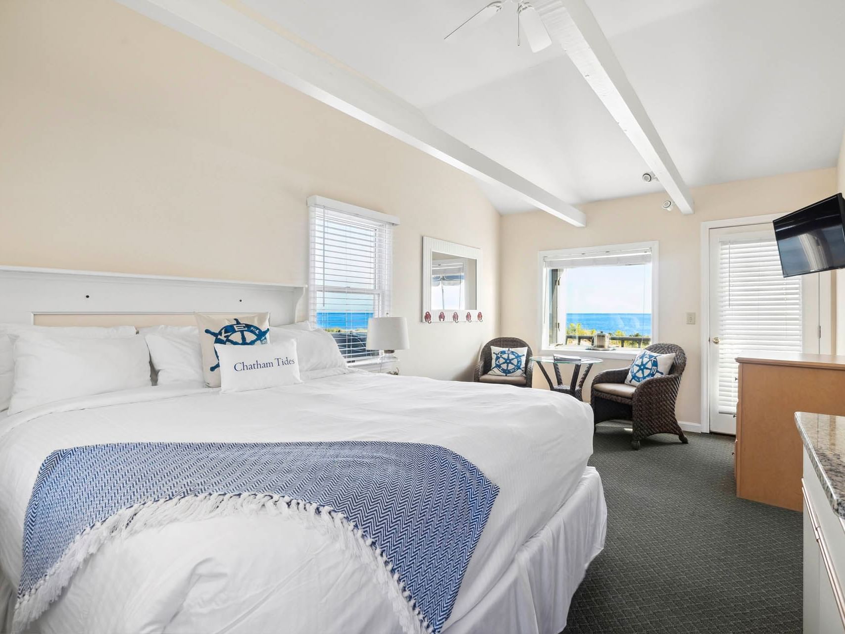 Double bed and seating area by the window in Oceantide Beachfront King Efficiency at Chatham Tides Resort