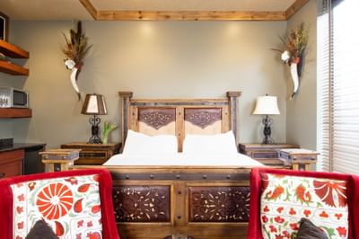 Large bed, lamps, & red comfy wing chairs in King Premiere Wild West at Retro Suites Hotel