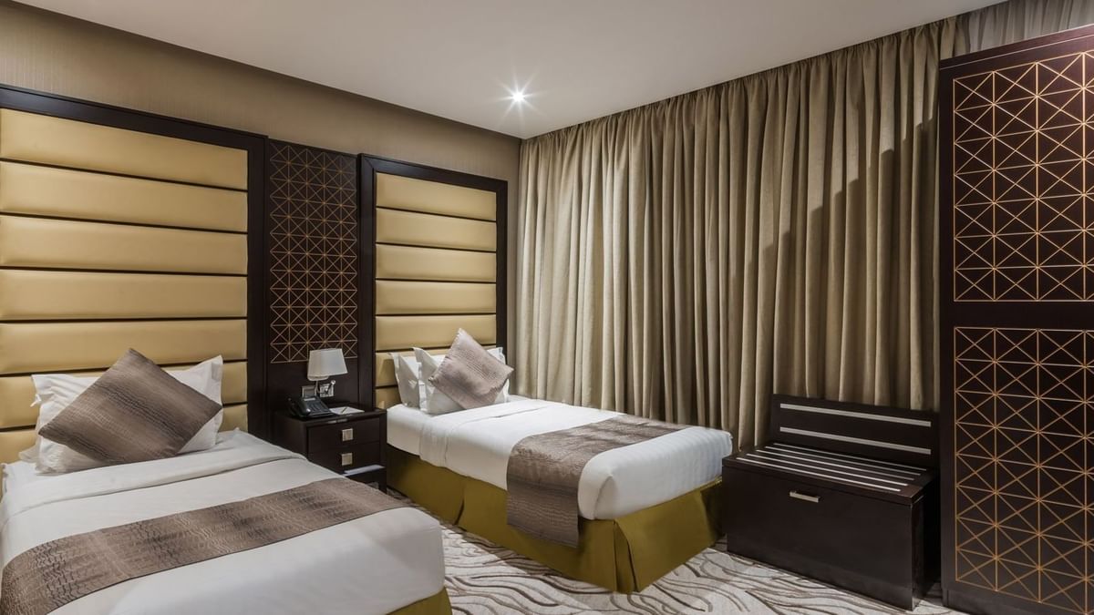 Twin beds with padded headboards by a dark wood dresser in Family Suite at Naviti by Warwick Al Khobar