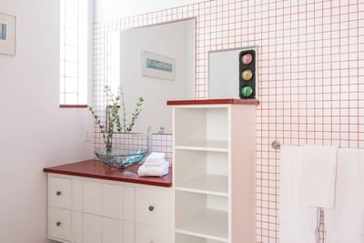 Bathroom vanity with glass basin, mirror, cupboard & towel rack in Queen Premiere La Rouge at Retro Suites Hotel