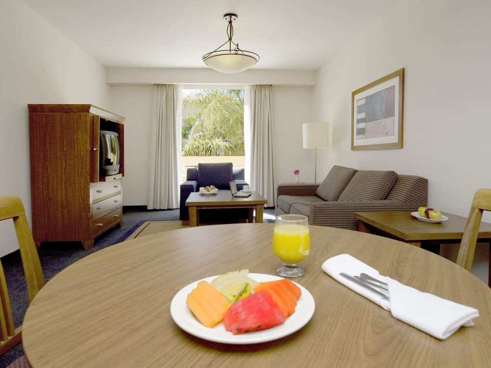 A fruit plate & a drink on table in Junior Suite at Fiesta Inn
