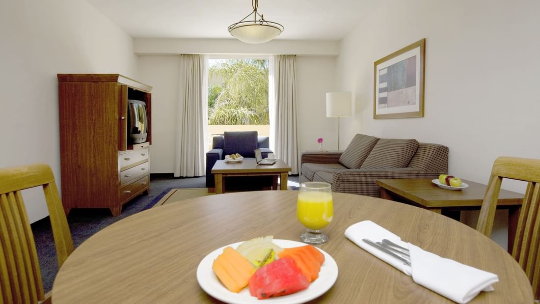A fruit plate & a drink on table in Junior Suite at Fiesta Inn