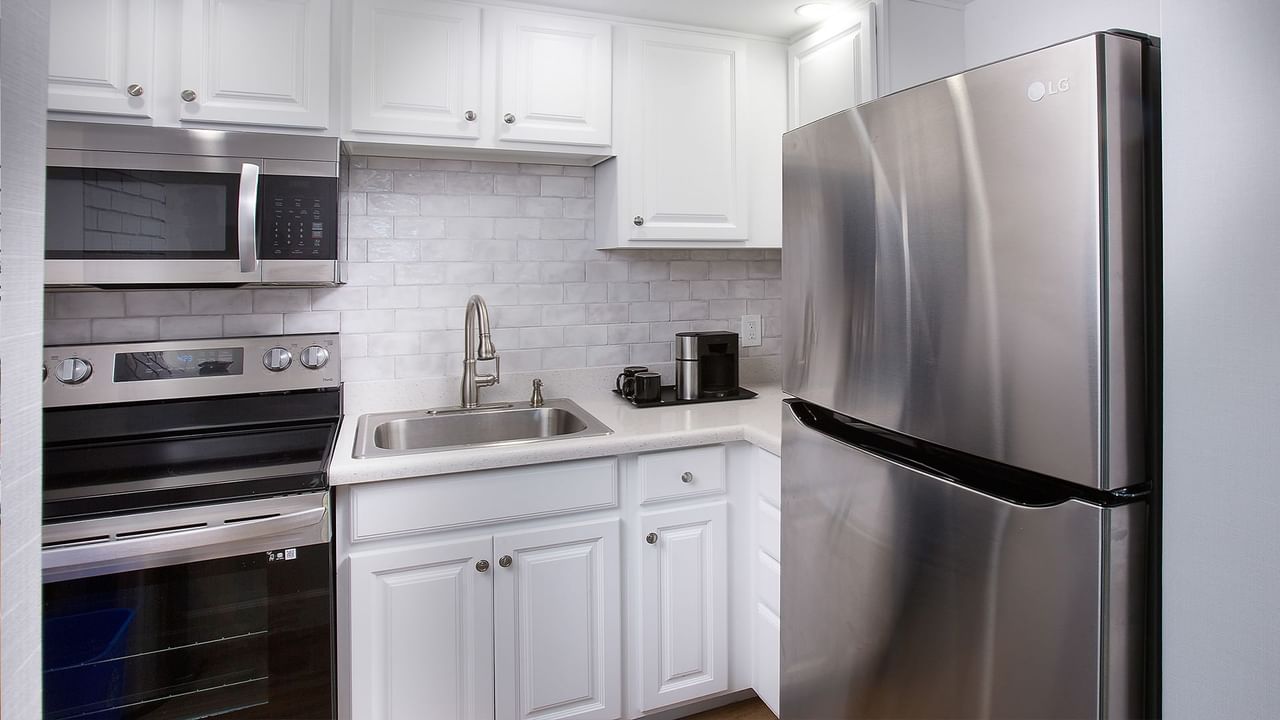 Modern kitchen with white cabinets, stainless steel appliances, and a sink with a faucet.