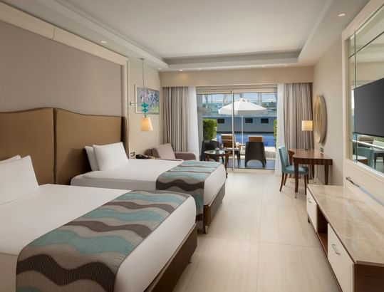Spacious suite with two beds, seating area, and terrace with pool access at Titanic Deluxe Golf Belek, Antalya.