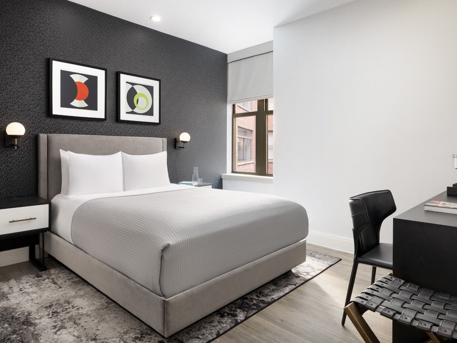 Modern queen bedroom with dark accent wall, geometric artwork, and work desk at ArtHouse Hotel New York City