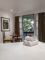 White bed by a round table under a framed art piece near a balcony in Warwick Deluxe Rooms at Warwick Fiji Resort and Spa