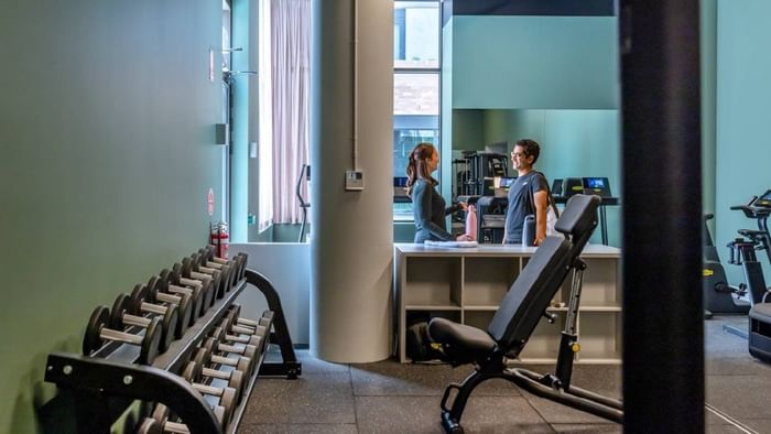 Modern gym with dumbbells, weight bench, and cardio equipment in Kensington at Swift Walk