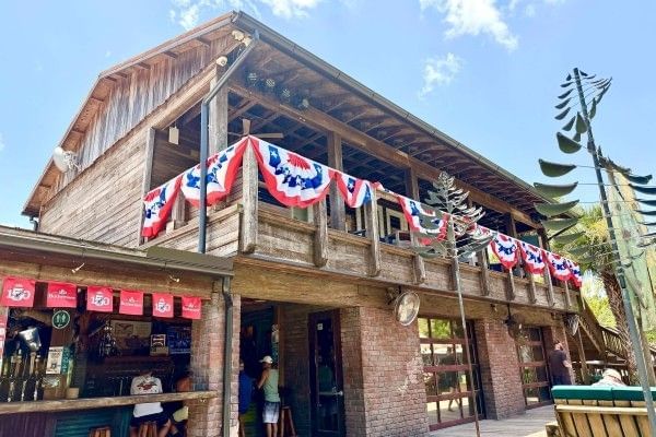 A large, wooden building with patriotic flags hanging from the balcony of the second story.