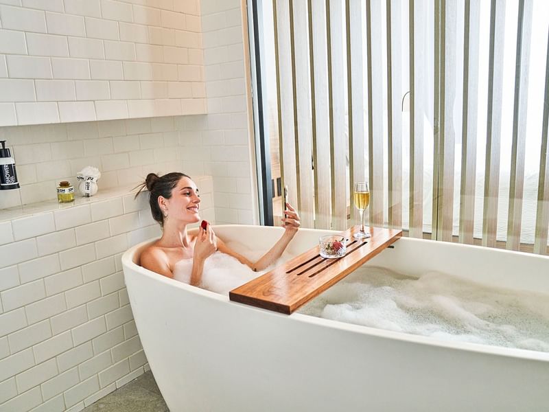 Lady relaxing in a bubble bath at IOH Freestyle Hotels