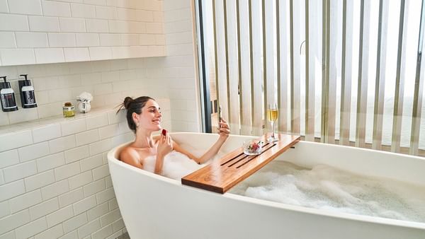 Lady having a bubble bath in Relax Room, 1 King at IOH Hotels