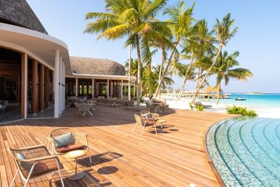 Luxurious seaside lounge at Ananea Madivaru Maldives with wooden decking, palm trees, and cozy seating overlooking the ocean