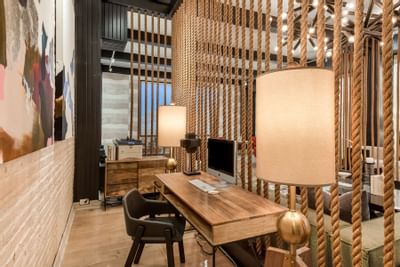 Wooden desk setup with iMac and decor elements in a 24-Hour Business Center with rope divider at The Riverwalk Plaza Hotel