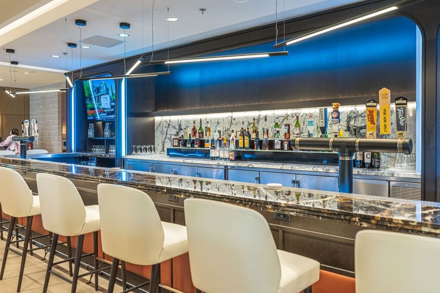 The Cannery Restaurant bar counter with white chairs, marble countertop, and shelves ss