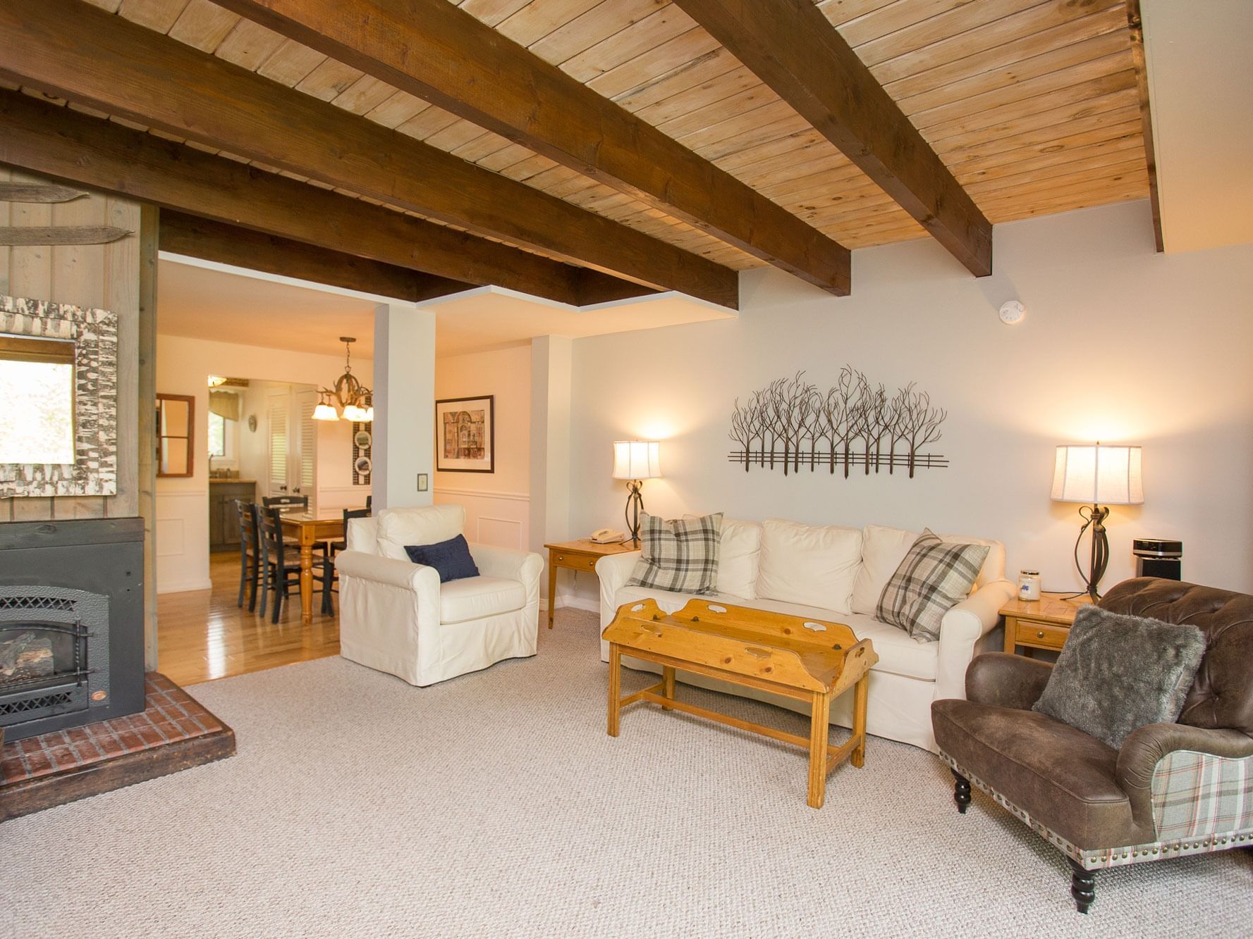 Spacious living room with exposed wood beam ceiling, white sofa, and fireplace at Topnotch Stowe Resort in Stowe.