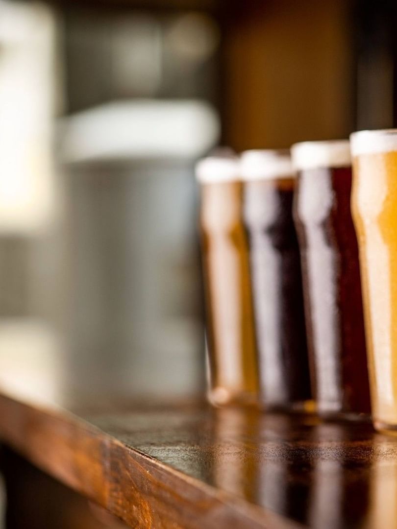 Row of craft beer glasses on a wooden counter at Hotel Barsey by Warwick