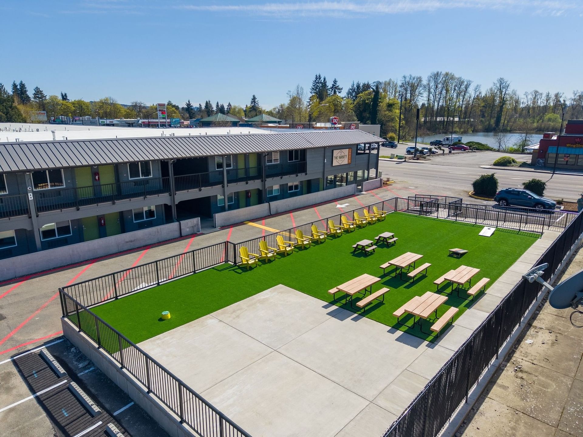 Artificial turf courtyard with yellow Adirondack chairs and picnic tables at The Varsity South
