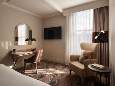 Cozy window seating in a bright Deluxe Double Room at The Met Hotel Leeds, England, with a mirror, TV, and work desk
