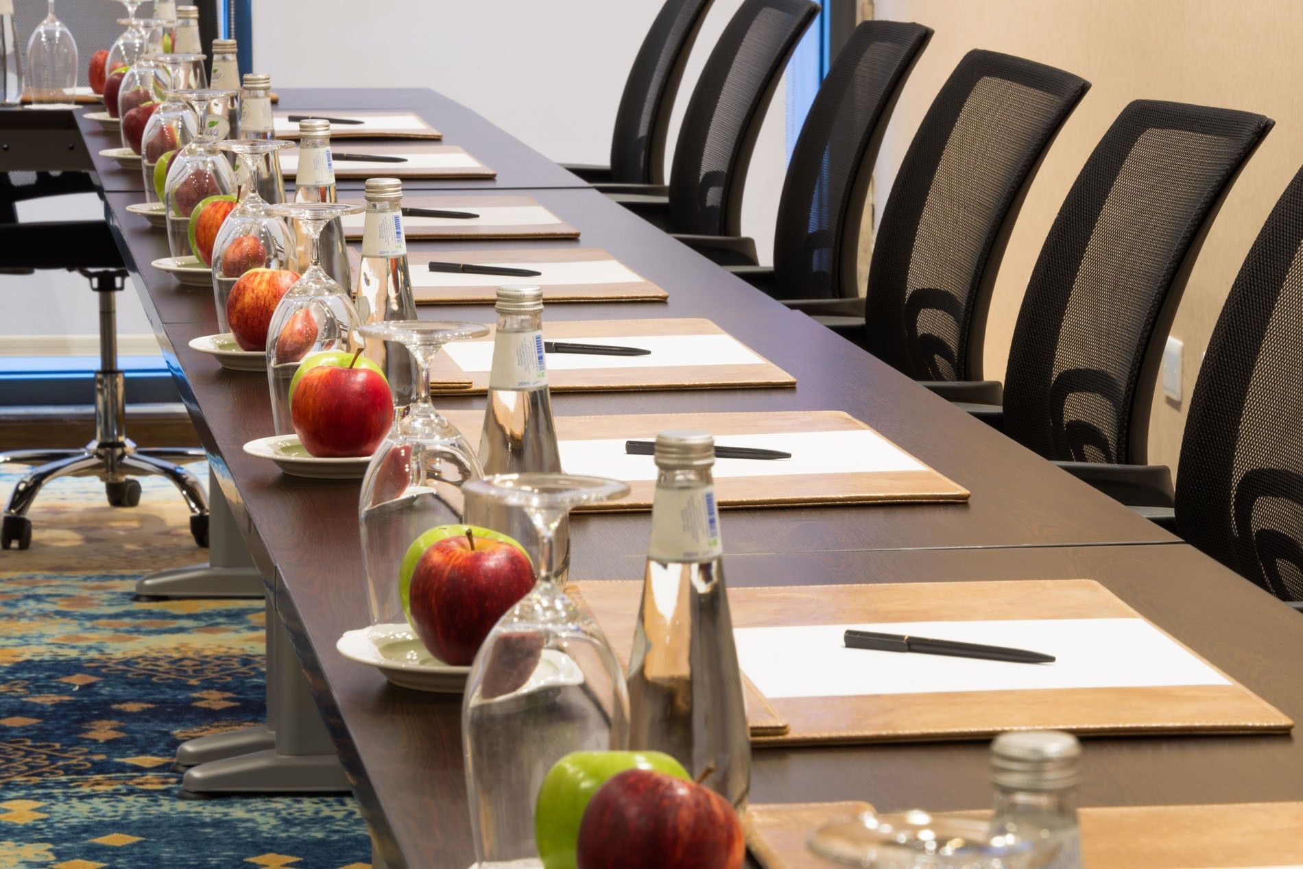 Conference table featuring apples by water bottles & rowed mesh chairs in Khaleej Meeting Room at Naviti by Warwick Dammam