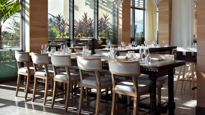 Wooden table elegantly set with glassware by the sunlit windows at The Residences at Seafire