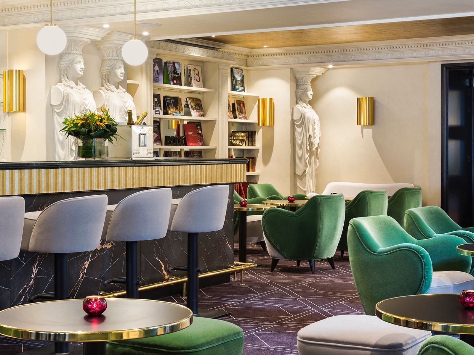 Elegant lounge area with green chairs, gold-accented tables, and statues at Warwick Corporate