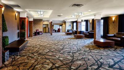 spacious, carpeted lobby of hotel with couches and tables