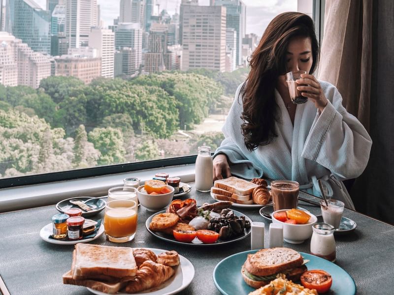 Lady having breakfast in a room with a city view at Pullman Sydney Hyde Park